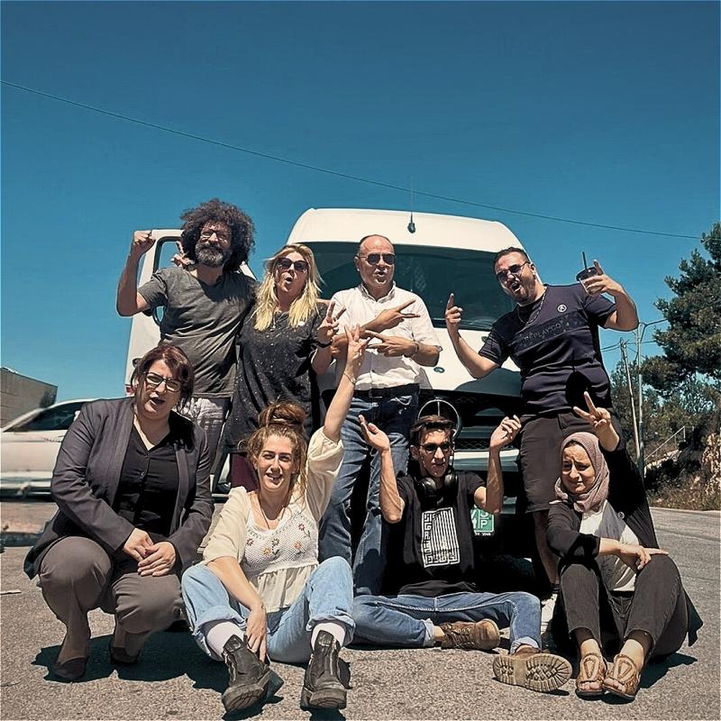 8 people posing in front of a white Mercedes van