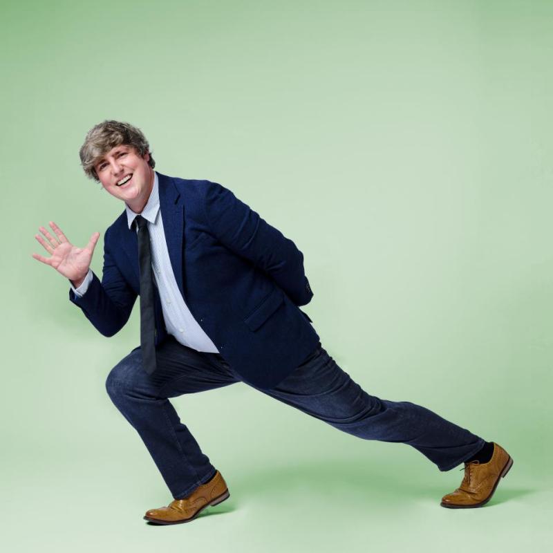 Glenn Moore in a deep lunge, smiling and waving at the camera.