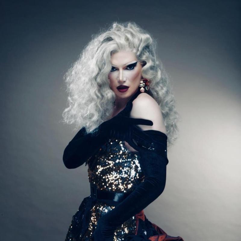Jonbers Blonde in a grey wig and wearing a ballgown with black opera gloves