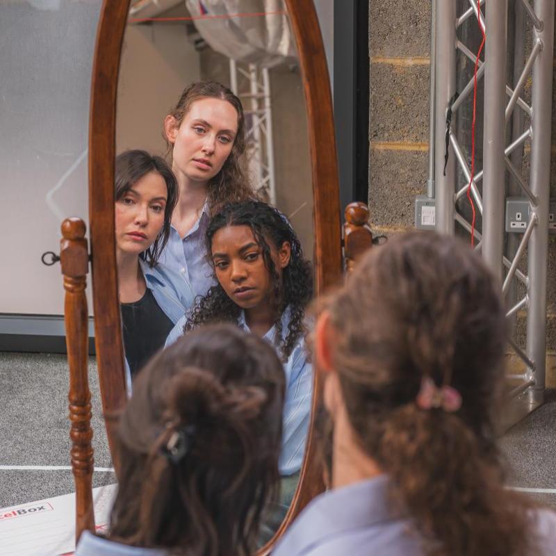 three women looking into a mirror