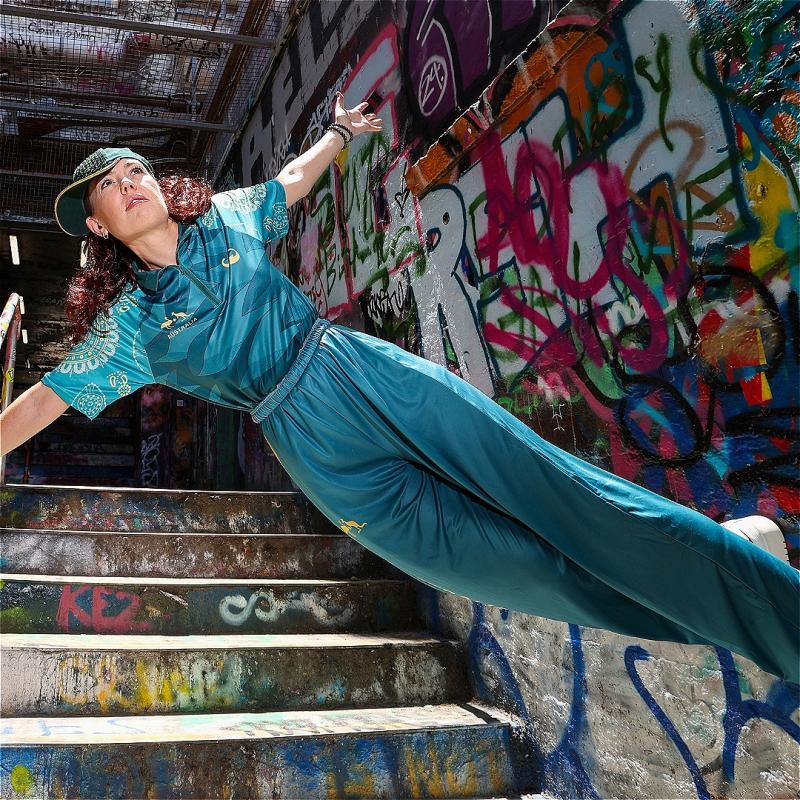 Woman standing sideways on a wall with graffiti.