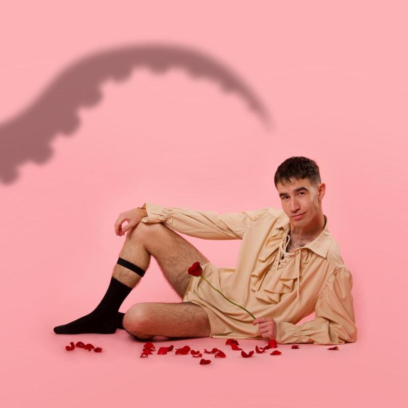 The performer lying seductively with rose petals scattered on the floor and a shadow of a tentacle on the left hand side.