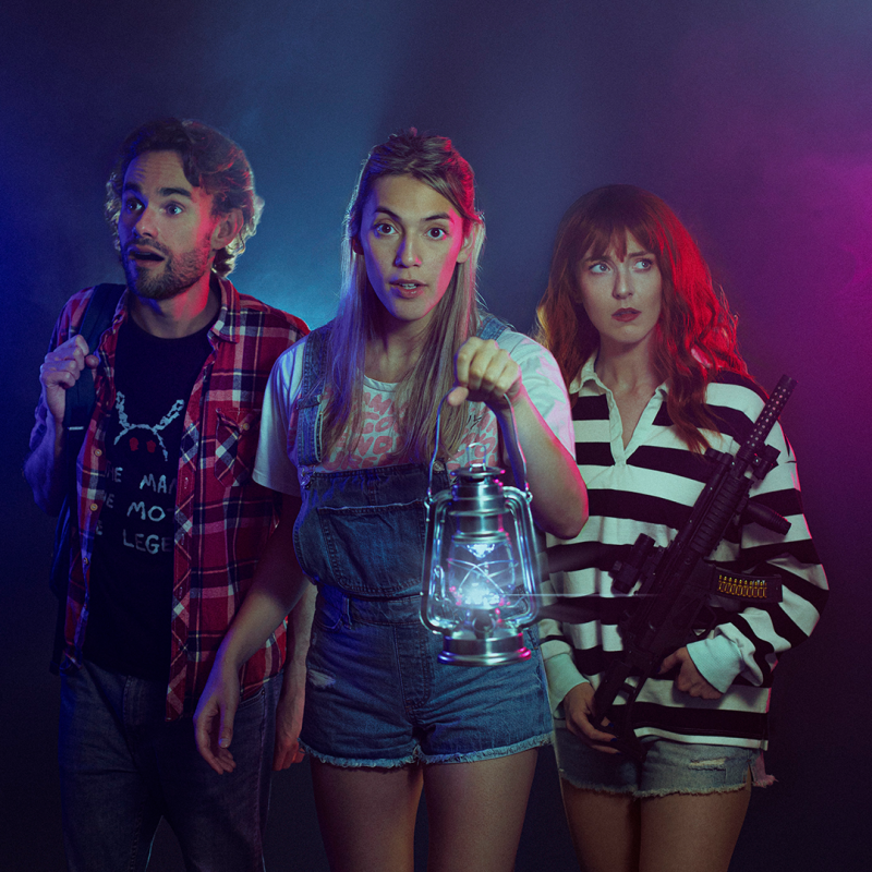 Three people dimly lit holding a lantern