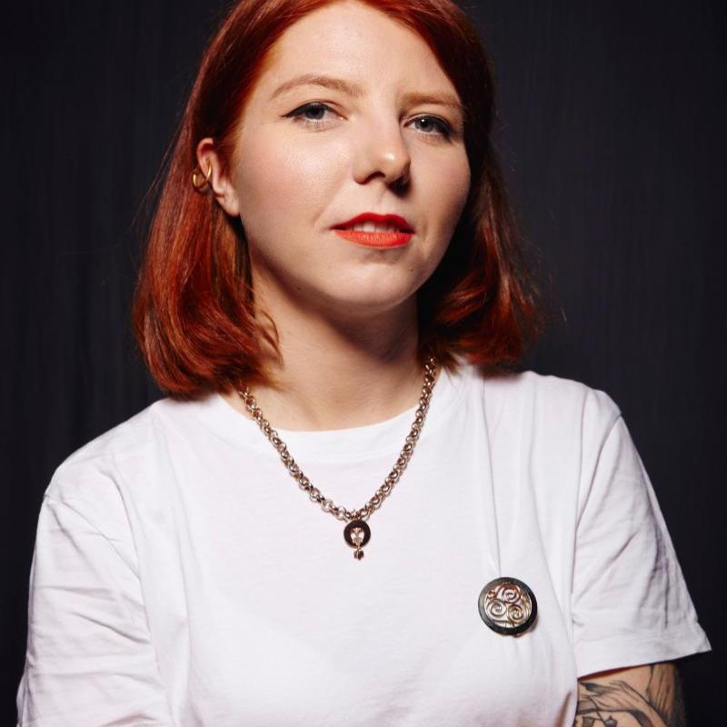 Marty looking at the camera with their arms crossed and wearing a white t-shirt.