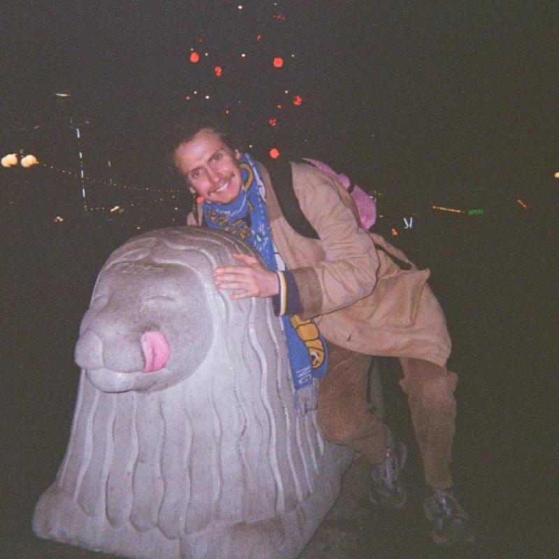 A film photo of Mikey posing with a statue