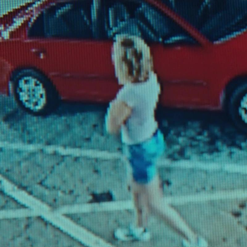 CCTV of a woman in a car park beside a red car
