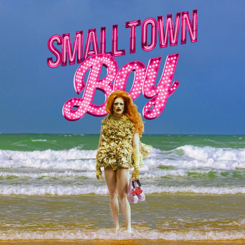 Smalltown Boy in pink lights behind someone holding shoes on a beach