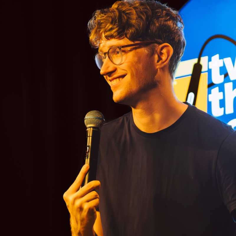 Photo of performer on stage holding a microphone.