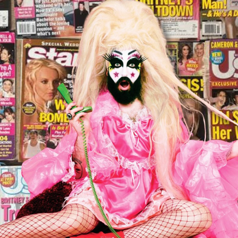 A fabulous looking Baby Lame wearing a pink dress and fishnets holds a green phone against a background of magazines featuring Britney headlines.