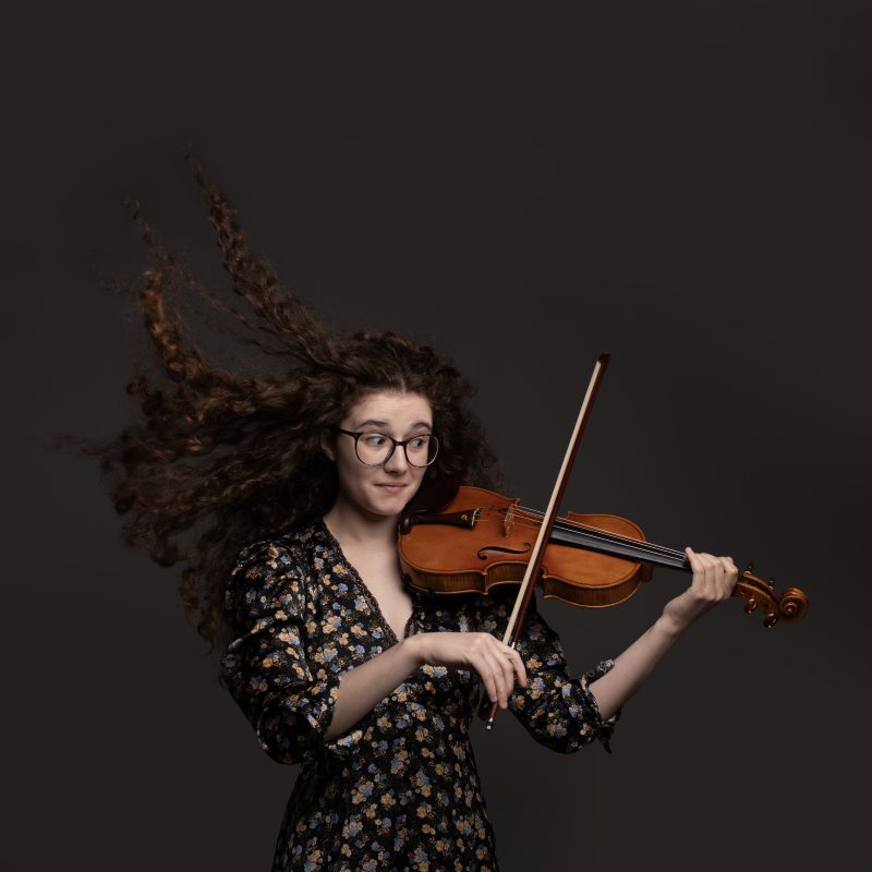 Photo of performer holding a violin, poised to play.