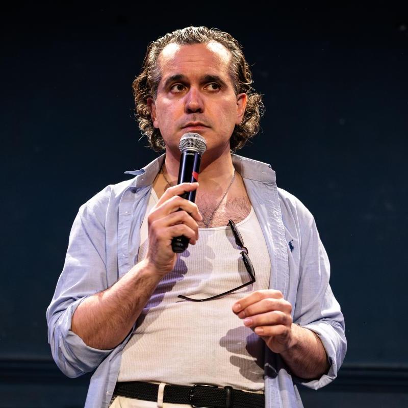 Sami holding a microphone performing stand up