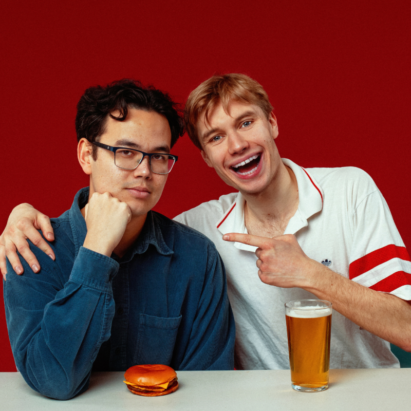 James and Ted sit next to each other jovially with a burger and a pint.
