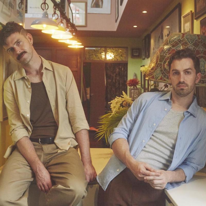 Two well dressed people in a cafe looking at the camera.
