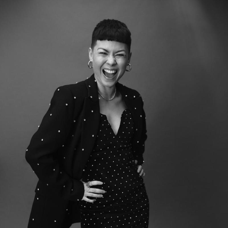 Black and white headshot of Anna wearing a dress full of sparkles and matching suit jacket.