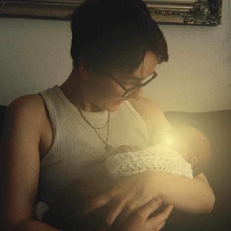 A person holding a newborn with a warm yellow light emitting from them.