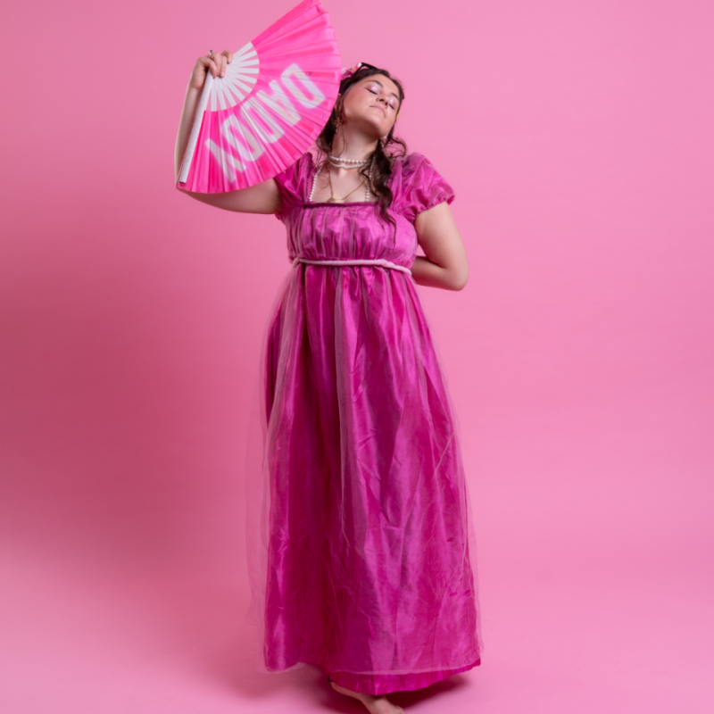 Photo of Clementine in pink period dress holding a fan with the text DADDY printed on it.