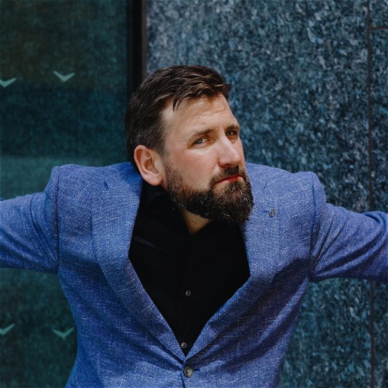 Garrett looking quizzically at the camera wearing a blue suit.