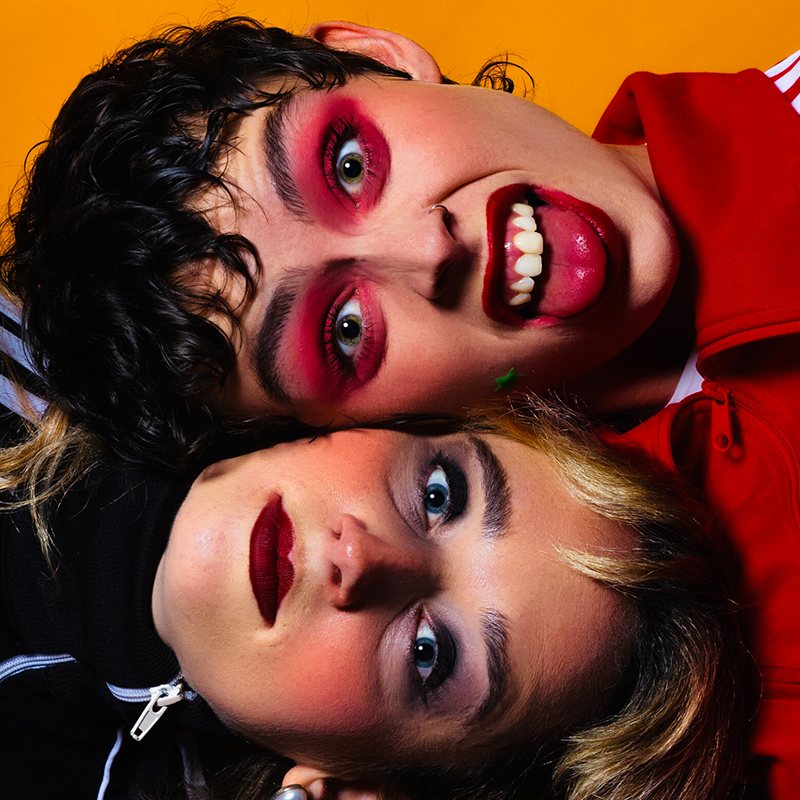 Close up photo of wo performers with their heads laid on top of one another.