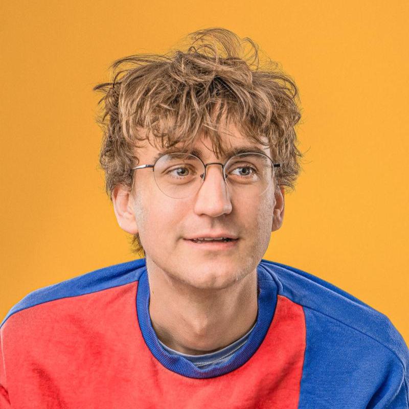 Headshot of Sam wearing a bright colourful jumper.