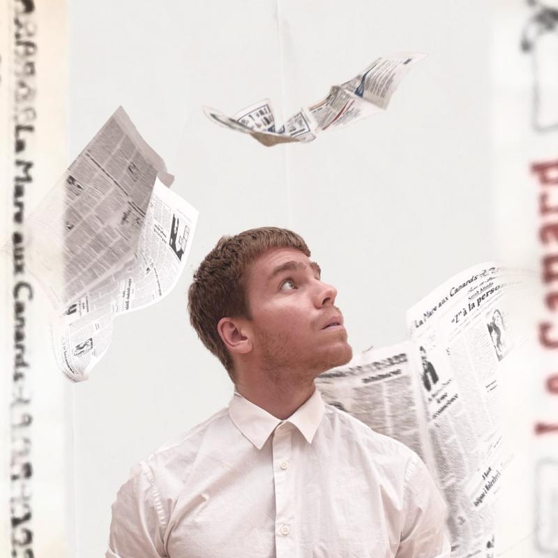 A man looks up quizzically whilst newspapers fall around him.