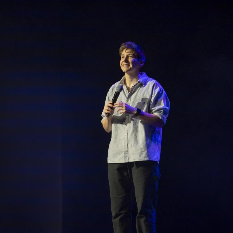 On stage of photo of Sarah looking relaxed and holding a microphone.