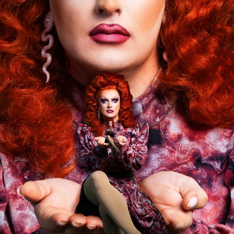 Kate Butch, wearing a red patterned dress and snake earrings, is cupping her hands in front of her and holding a smaller version of herself 