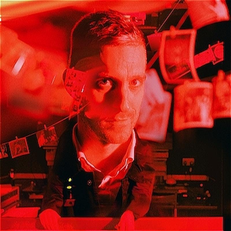 Red and black coloured image of man with photographs hanging on a clothesline