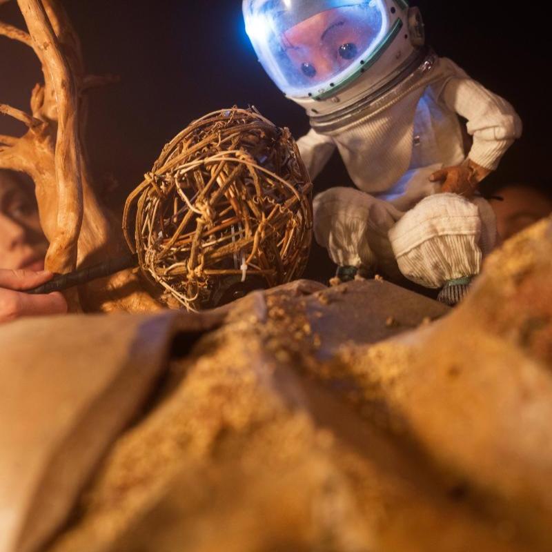 Space Person on desert planet looking at tumbleweed