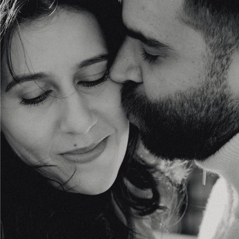 A black and white close-up image of the performers. One is being kissed on the cheek.