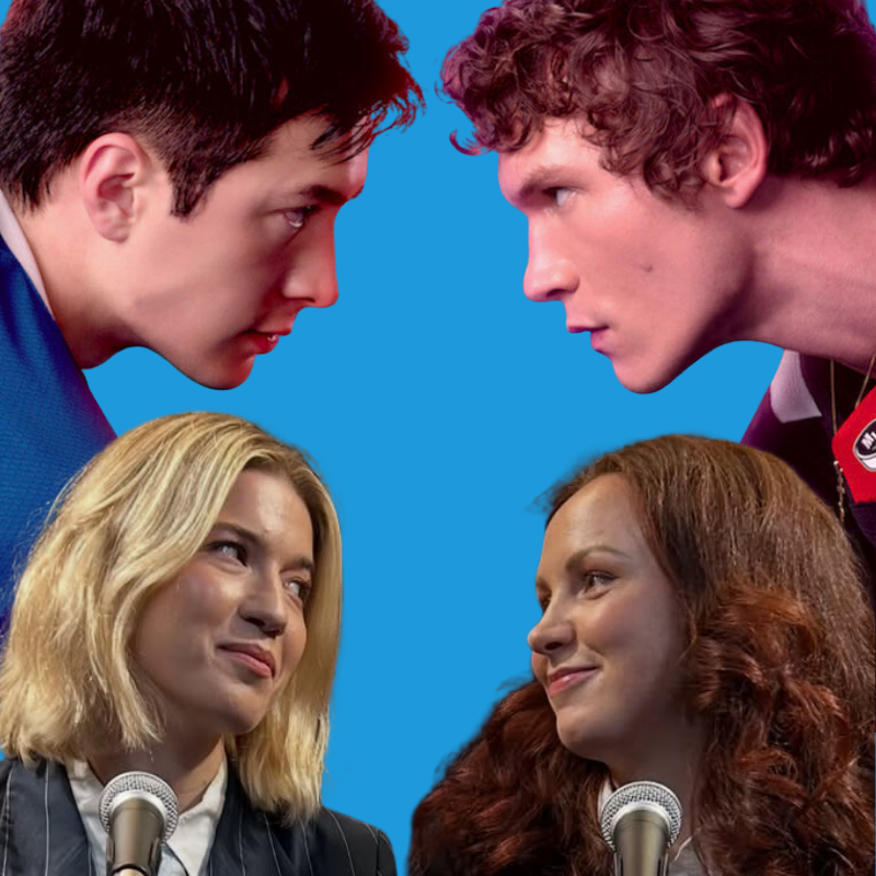 Two female comedians are in front of microphones against a backdrop with the main characters Shane and Ilya from Heated Rivalry