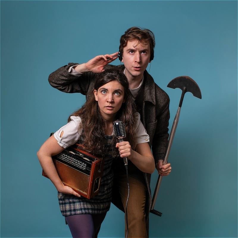 A white woman with long brown hair and a white man with short brown hair are standing together looking up intensely, in front of a blue background. The woman is holding an old timey radio and microphone, and the man is holding a shovel and wearing black headphones.
