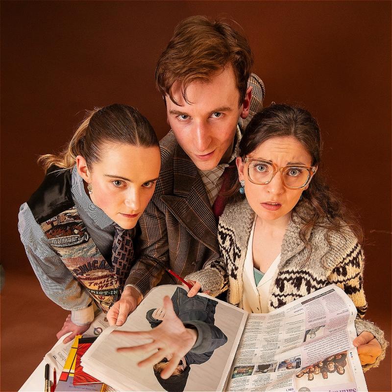 A vintage-looking scene of three people gathered around a table. The three individuals are leaning in closely and looking upward toward the camera with slightly concerned expressions. On the table there are various items including an open newspaper, a magazine and passports.