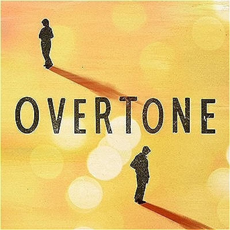 A birds eye image of two individuals far apart and turned away from one another. The play's title 'overtone' stands between the two individuals.