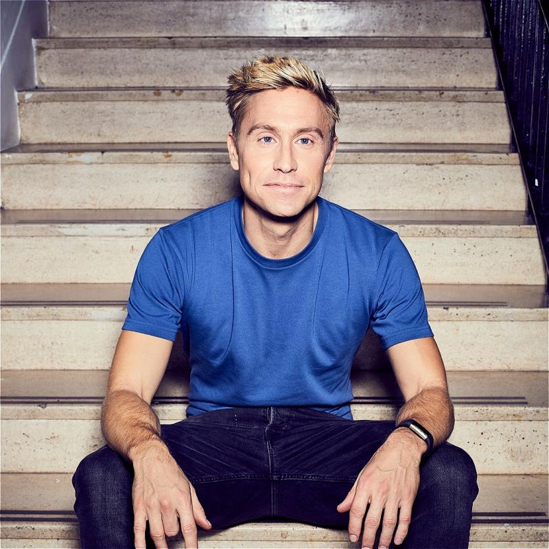 Russell sitting on stairs with a bemused expression on his face.
