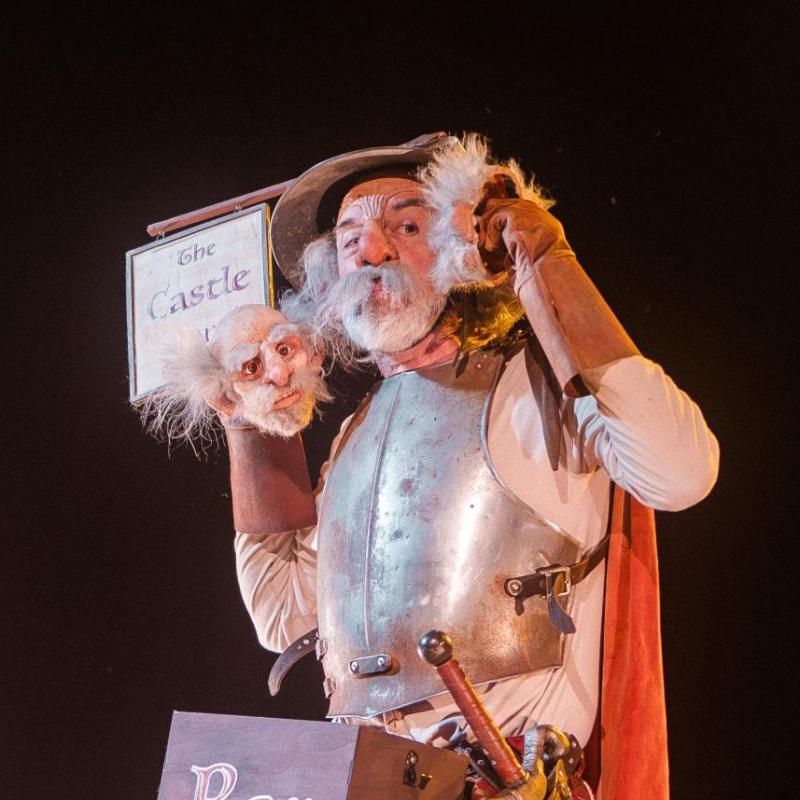 Don Quixote conversing with two small puppet heads