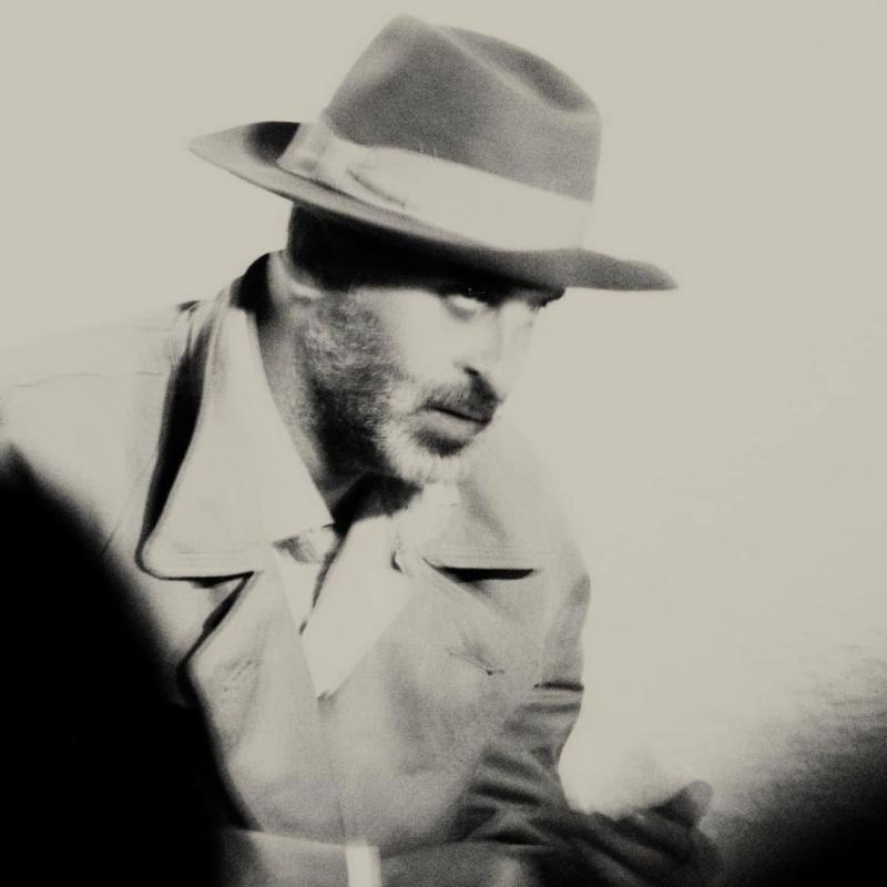 A blurry, black and white image of a person staring intensely to the side. 