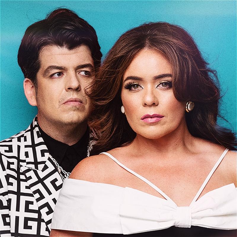 The performers serving face to the camera against a blue background