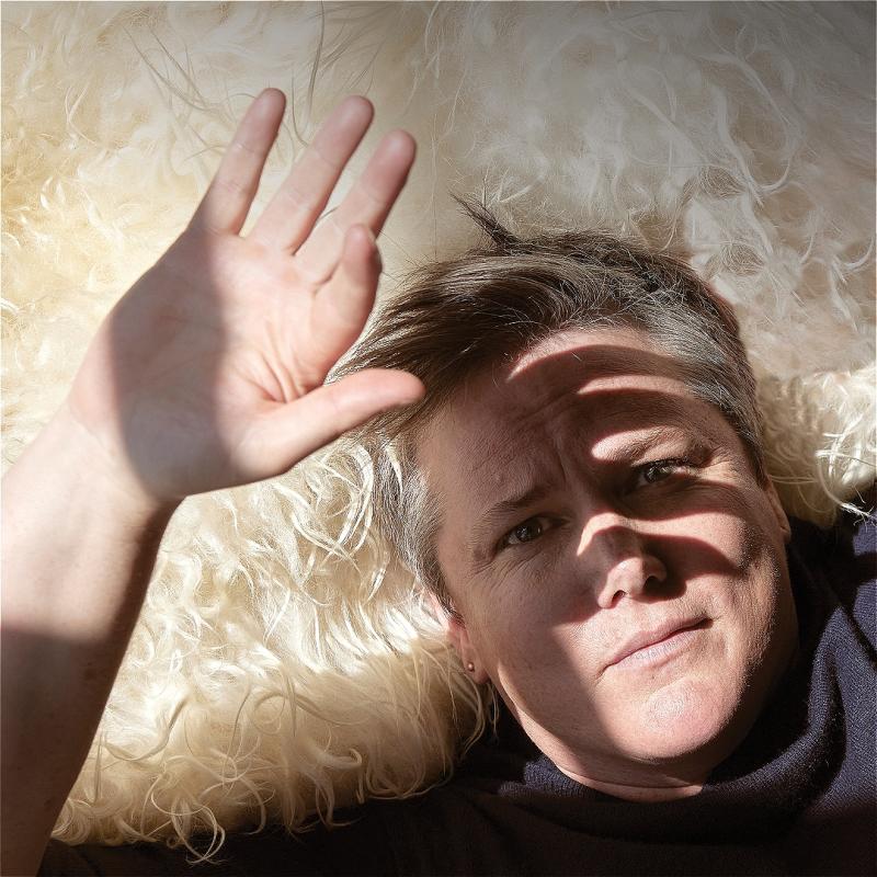 Hannah lying on a white rug, shielding their face from the sun.