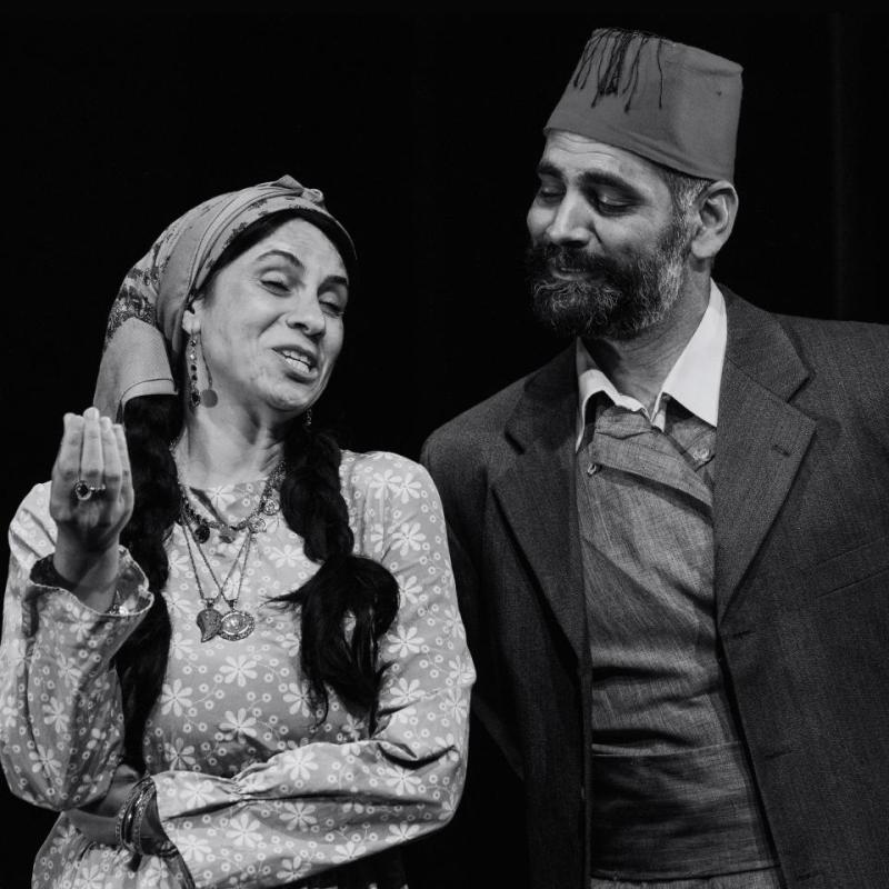 A man and a woman look engaged in happy conversation, against a black background.