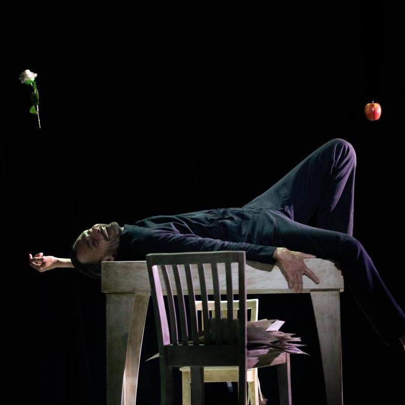 Photo of man lying down on a table, with a dark backdrop
