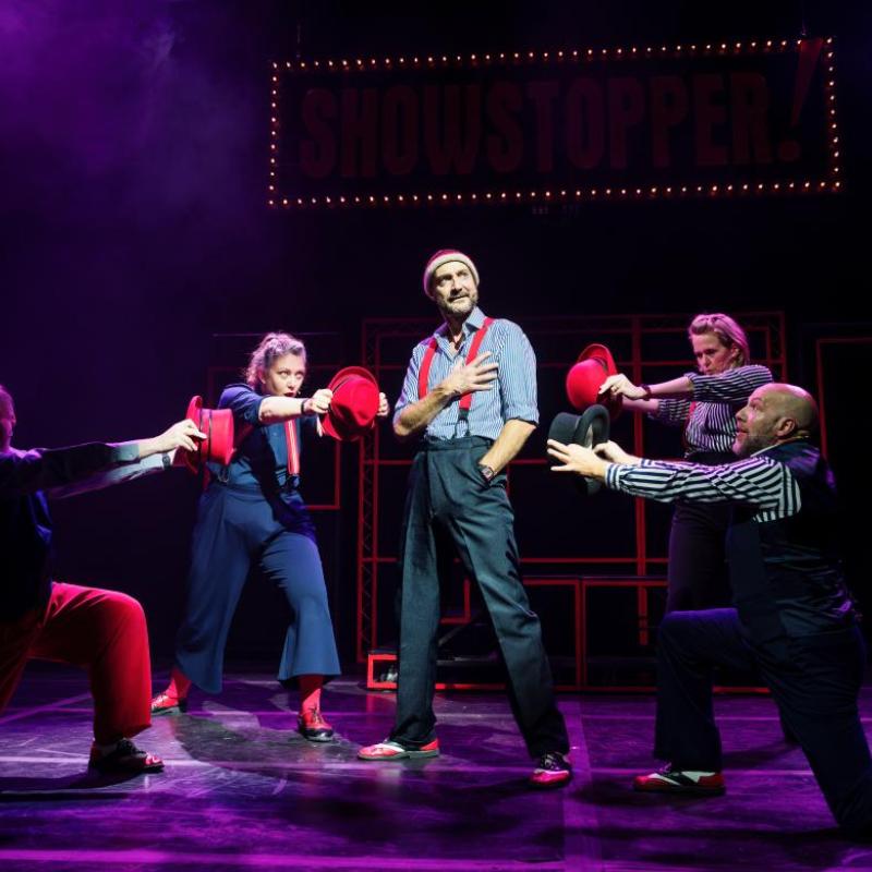 Purple spotlight on performers holding red hats