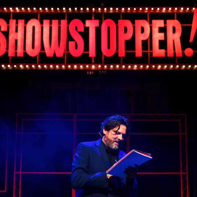 Image showing man writing in a notebook in front of the 'Showstopper!' sign