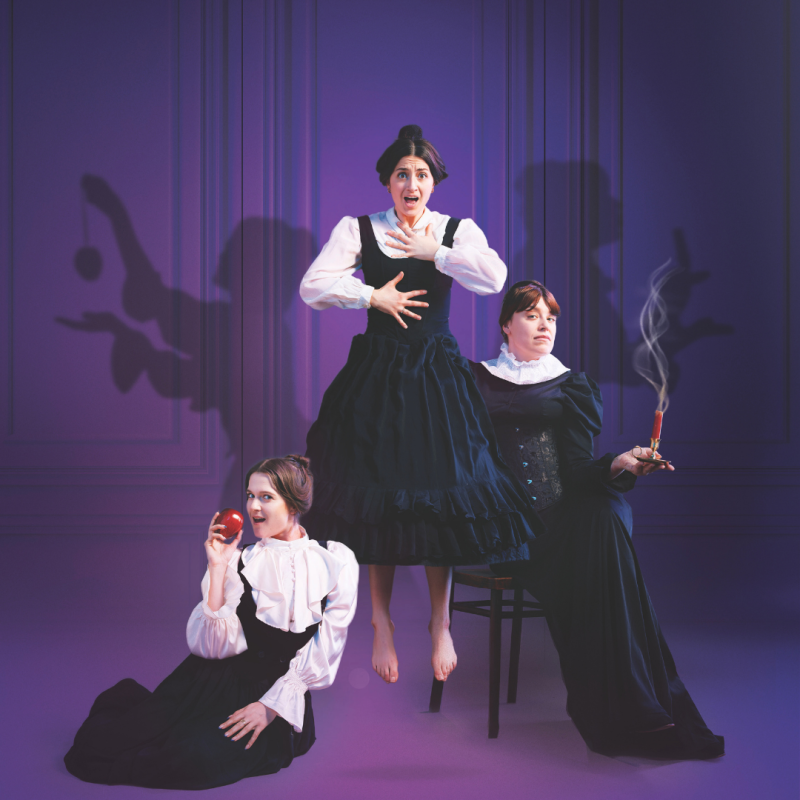 Three women in period dress: one holding an apple, one holding a lit dynamite and one levitating.