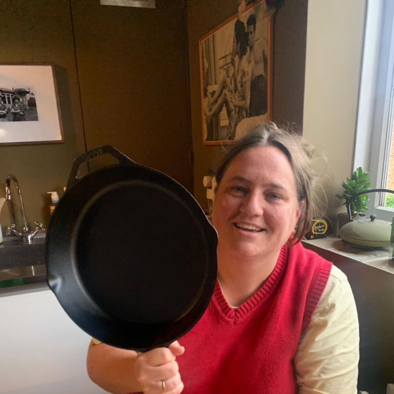 Alice Sneddon holding up a frying pan in a kitchen