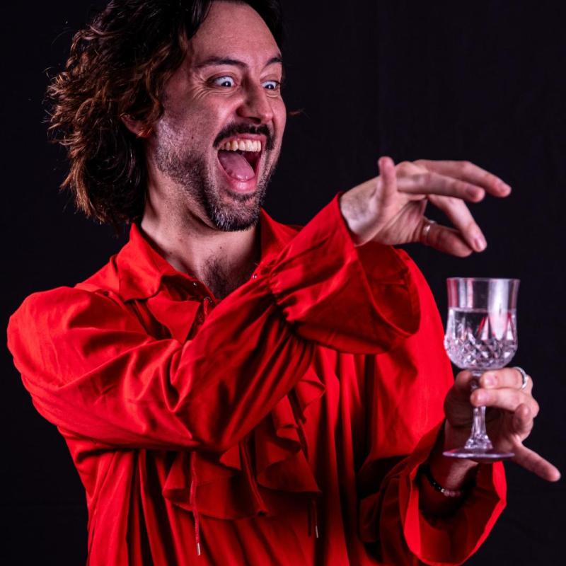 A maniacally laughing vampire crumbles poison into a Champagne glass.