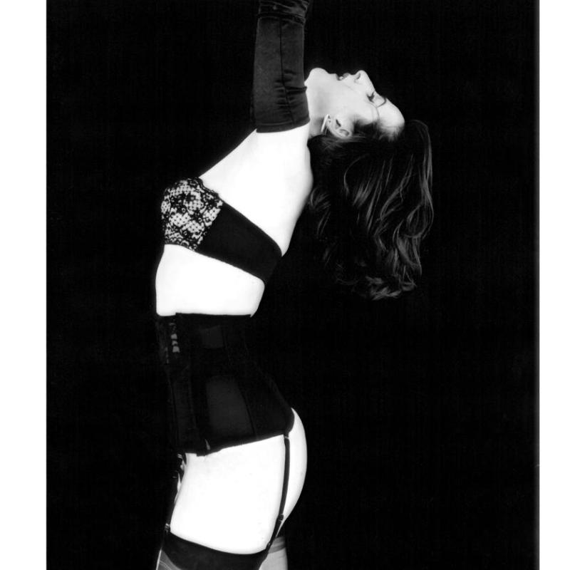 A black and white image of a woman in underwear and reaching upwards. 